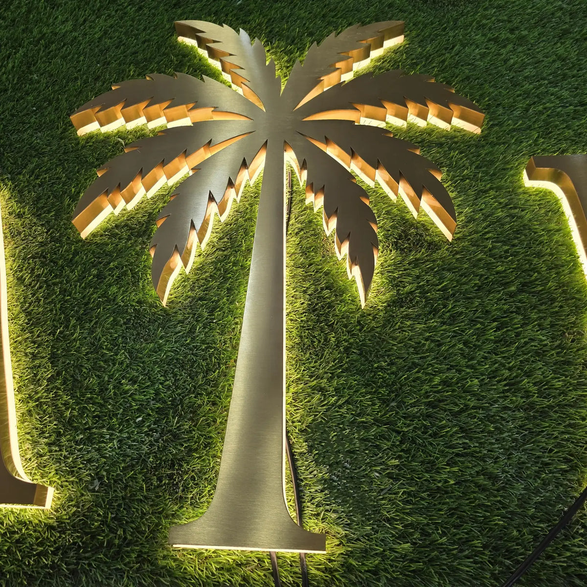 Gold brushed stainless steel backlit palm tree sign with warm LED halo
