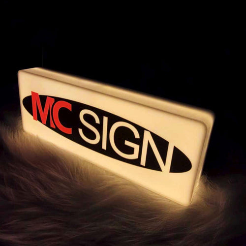 Illuminated acrylic LED light box logo sign, angled view at night